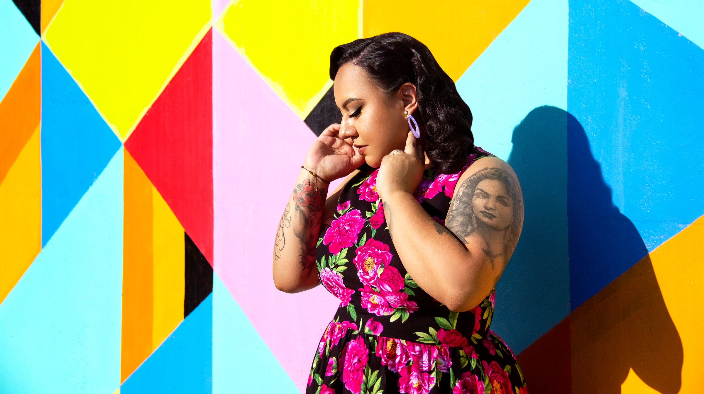 Woman in a floral dress standing against a colorful geometric background